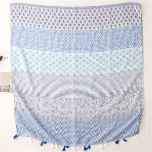 Detail of blue and white scarf featuring layered geometric patterns and soft fringe trim