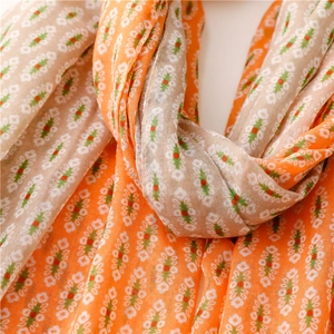 Detail of bohemian scarf showing soft orange and beige striped fabric with floral print
