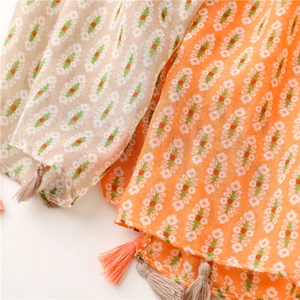 Detail of bohemian floral print scarf with soft fringe edges in orange and beige