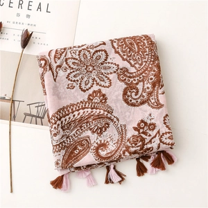 Detail of pink bohemian scarf with paisley patterns and decorative tassels on white background
