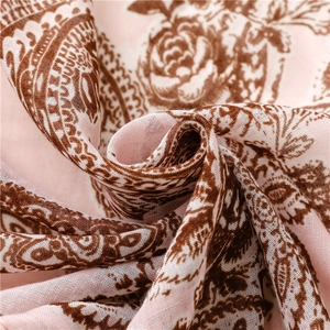 Detailed close-up of pink paisley floral scarf fabric texture and tassel fringe