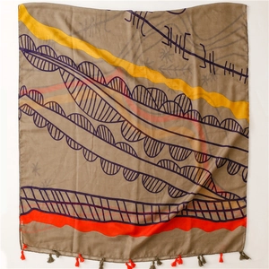 Detailed view of bohemian map pattern scarf with decorative red and brown tassels