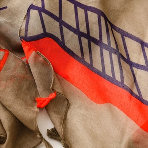 Close-up of lightweight brown scarf with orange stripe and handmade fringe tassels