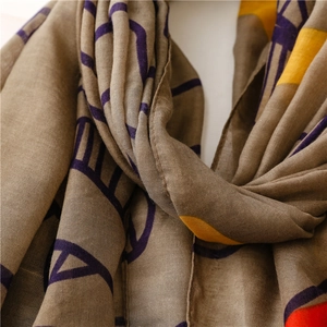 Close-up of map pattern scarf showing knit texture and earthy tones with tassels