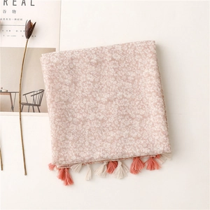 Détail d'une écharpe florale rose clair avec des franges délicates et un tissu doux
