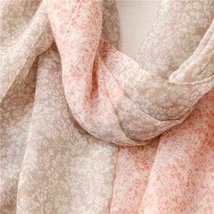 Gros plan d'une écharpe florale légère au tissu doux rose et beige délicat