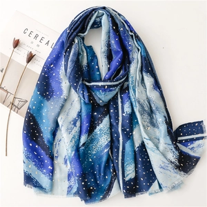 Blue and white gradient scarf with gold foil accents and fringe, displayed with props