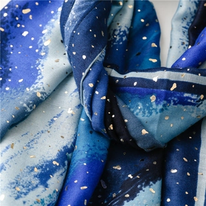 Close-up of soft scarf featuring deep blue ink painting texture and gold foil star pattern