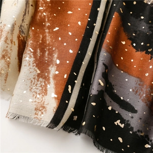 Detailed view of winter shawl showing gold foil abstract print and fringe texture