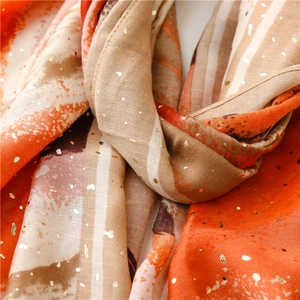 Macro detail of scarf with abstract orange gradient and shimmering gold foil polka dots