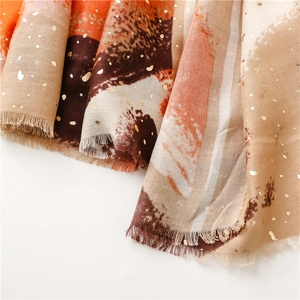 Detail of orange and beige scarf with golden foil dots and delicate fringe edges