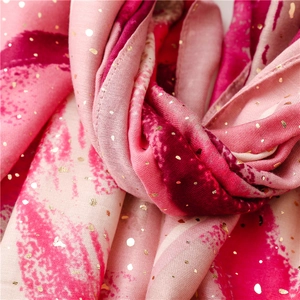Close-up of artistic scarf texture with gold foil dots and pink brushstrokes