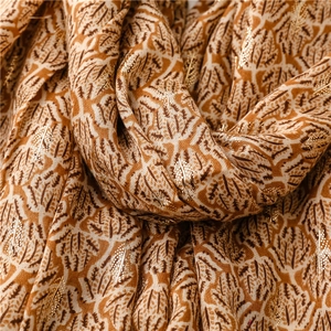 Macro shot of cotton linen scarf texture featuring golden botanical patterns and warm tones