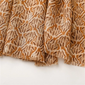 Detailed macro view of soft scarf fabric with gold leaf prints and fringed edges