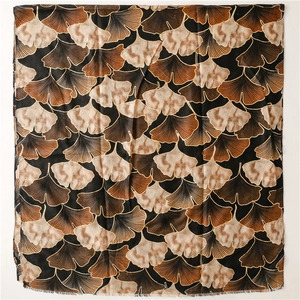 Detail of soft cotton-linen scarf with golden ginkgo leaf pattern on black background