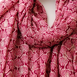 Detail of magenta scarf with beige leaf patterns and sparkling gold foil texture