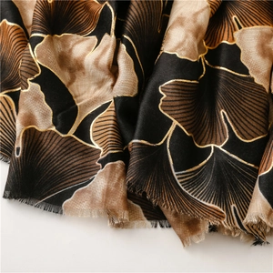 Detail of vintage linen scarf with golden ginkgo leaf patterns and soft fringe edges