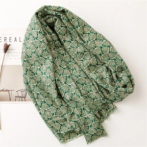 Detail of soft scarf with green leaf pattern on white cotton linen blend fabric
