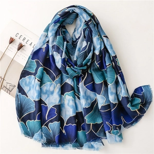 Blue ginkgo leaf print scarf with gold trim shown from a 45-degree angle