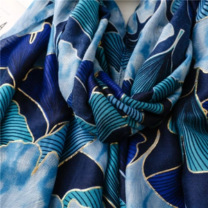 Detailed macro view of blue cotton-linen scarf with golden ginkgo leaf foil print texture