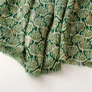 Close-up of green and cream leaf jacquard scarf with gold sequins and fringe