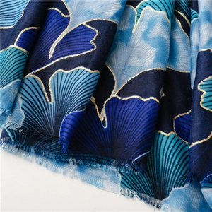 Close-up of golden ginkgo leaf patterns and fringe on a thick blue linen scarf