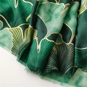 Close-up of green cotton linen scarf with gold foil ginkgo leaf pattern and frayed edges