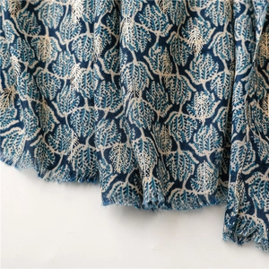 Detail of blue leaf pattern on cotton-linen scarf with gold foil and tassel trim