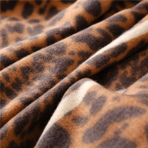 Macro shot of leopard print scarf fabric showing thick knit texture and soft cashmere feel