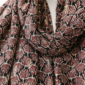 Detail of red and black cotton-linen scarf featuring gold foil leaf patterns and texture
