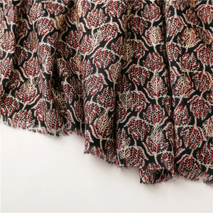 Detail of red and white leaf print scarf with gold foil dots and fringe edges