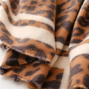 Detail of cashmere-like leopard print scarf featuring soft texture and fringe edges