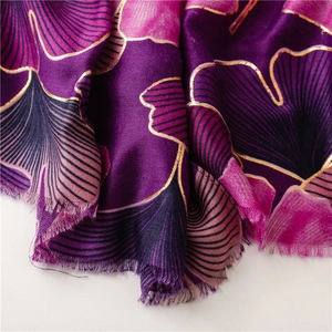 Macro detail of golden ginkgo leaf foil printing on smooth gradient purple scarf fabric