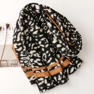 Detail of cashmere-like scarf with leopard print and orange stripes, raw fringe edges