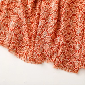 Macro detail of leaf pattern on orange linen scarf with silver metallic thread and tassels