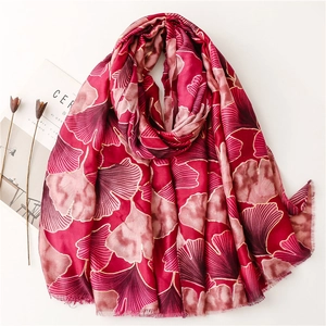 Detailed shot of red linen scarf with gold-edged ginkgo leaf pattern and fringe trim