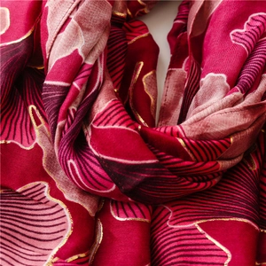 Detail of red cotton linen scarf with golden ginkgo leaf patterns and metallic embroidery