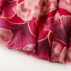 Macro detail of red scarf with golden ginkgo leaf patterns and fringe edges