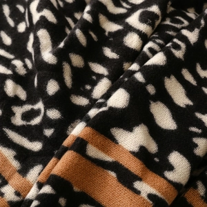 Close-up of leopard print cashmere feel scarf with soft texture and brown striped edge