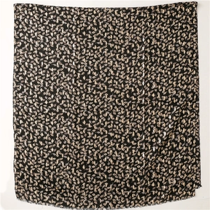 Detailed view of black scarf featuring golden leaf patterns and soft fringe edges