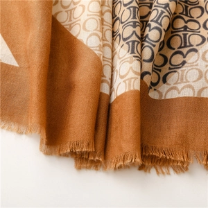 Dettaglio dello scialle pashmina marrone e beige con stampa logo e frange fini