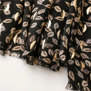 Detail of black cotton-linen scarf with gold foil leaf patterns and fringed edges