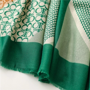 Dettaglio di sciarpa in cotone e lino verde smeraldo con motivi geometrici e frange