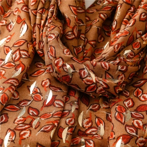 Macro detail of caramel brown scarf with metallic gold foil leaf prints and soft fabric