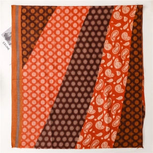 Detail of paisley and polka dot patterns on a warm orange cashmere-like scarf