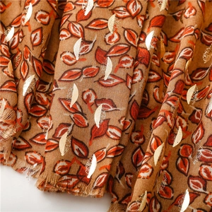 Detail of soft brown linen feel scarf with vibrant orange and gold foil leaf patterns