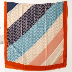 Dettaglio di sciarpa color-block con motivi logo e trama delicata con bordi a frange