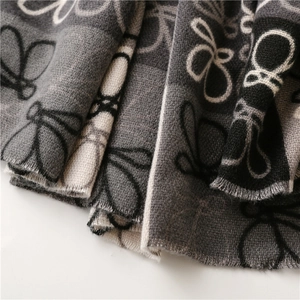 Detailed view of butterfly pattern woven on a thick grey and black cashmere-like scarf