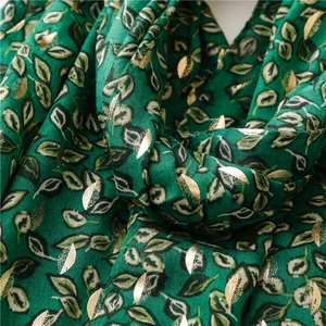 Macro shot of dark green linen-feel scarf with elegant gold leaf foil printed textures