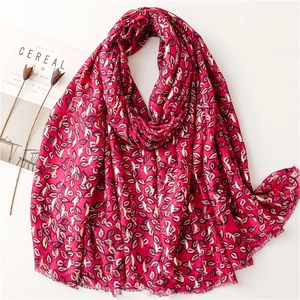 Close-up of rose red cotton-linen scarf with gold foil leaf patterns and fringed edges